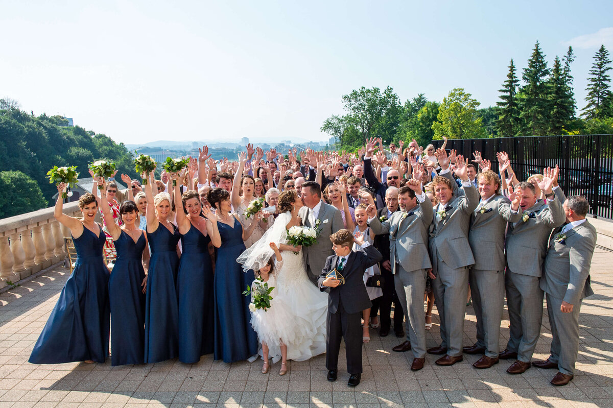 large group photo of an Ottawa birde and groom, their bridal party and all their guests on the terrace of the Chateau Laurier wedding venue.  Captured by Ottawa wedding photographer JEMMAN Photography