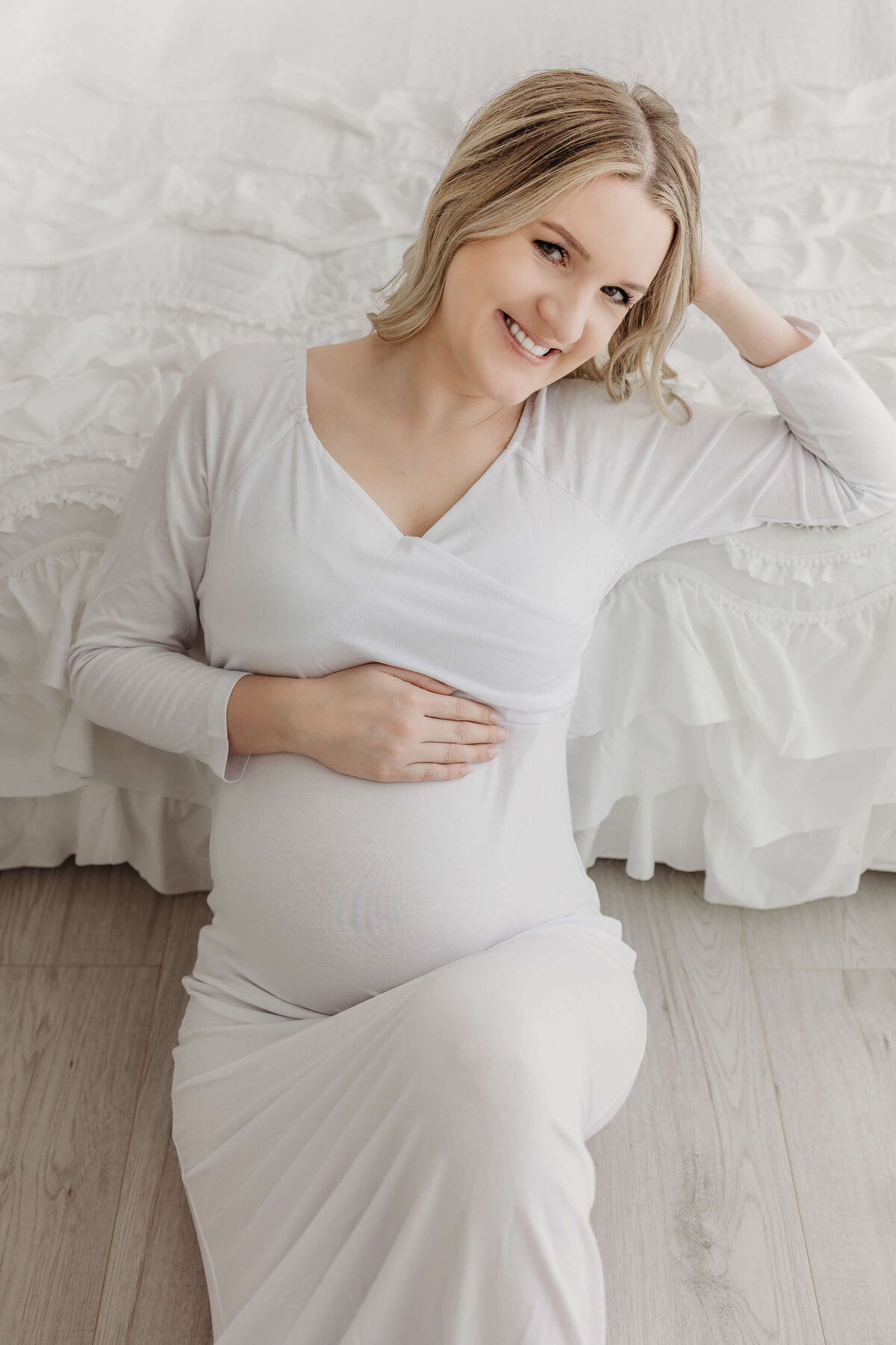 Happy woman expecting baby in all white dress near Eau Claire, WI