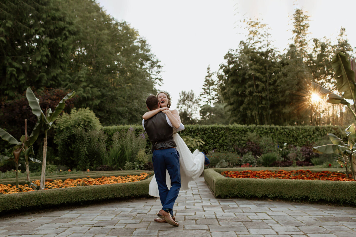 A bride and groom playfully embrace in a garden during sunset. Captured by Fort Worth Wedding Photographer, Megan Christine Studio