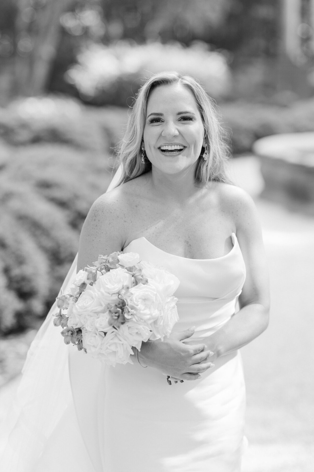 Black and white image of bride smiling holding her bouquet