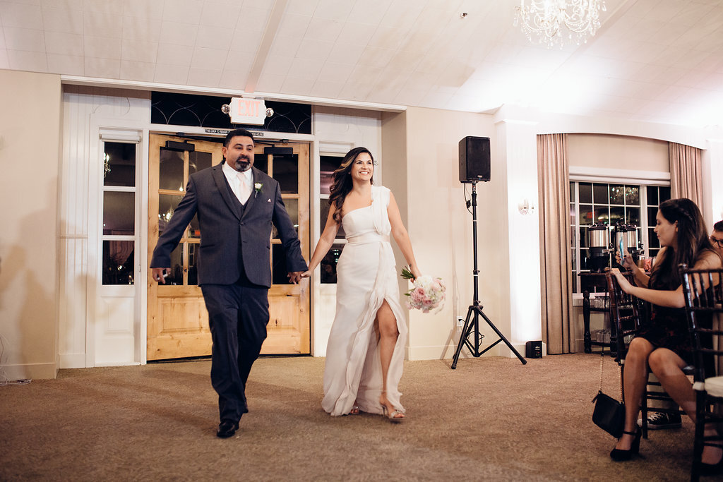 Wedding Photograph Of Groomsman And Bridesmaid Holding Hands While Entering The Reception Hall Los Angeles