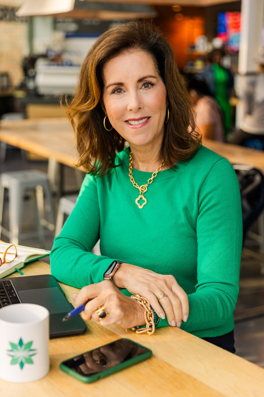 Consultant for creative people  Louise Pritchardworking in an Atlanta Buckhead coffee shop wearing a  green top by personal brand photographer Laure Photography