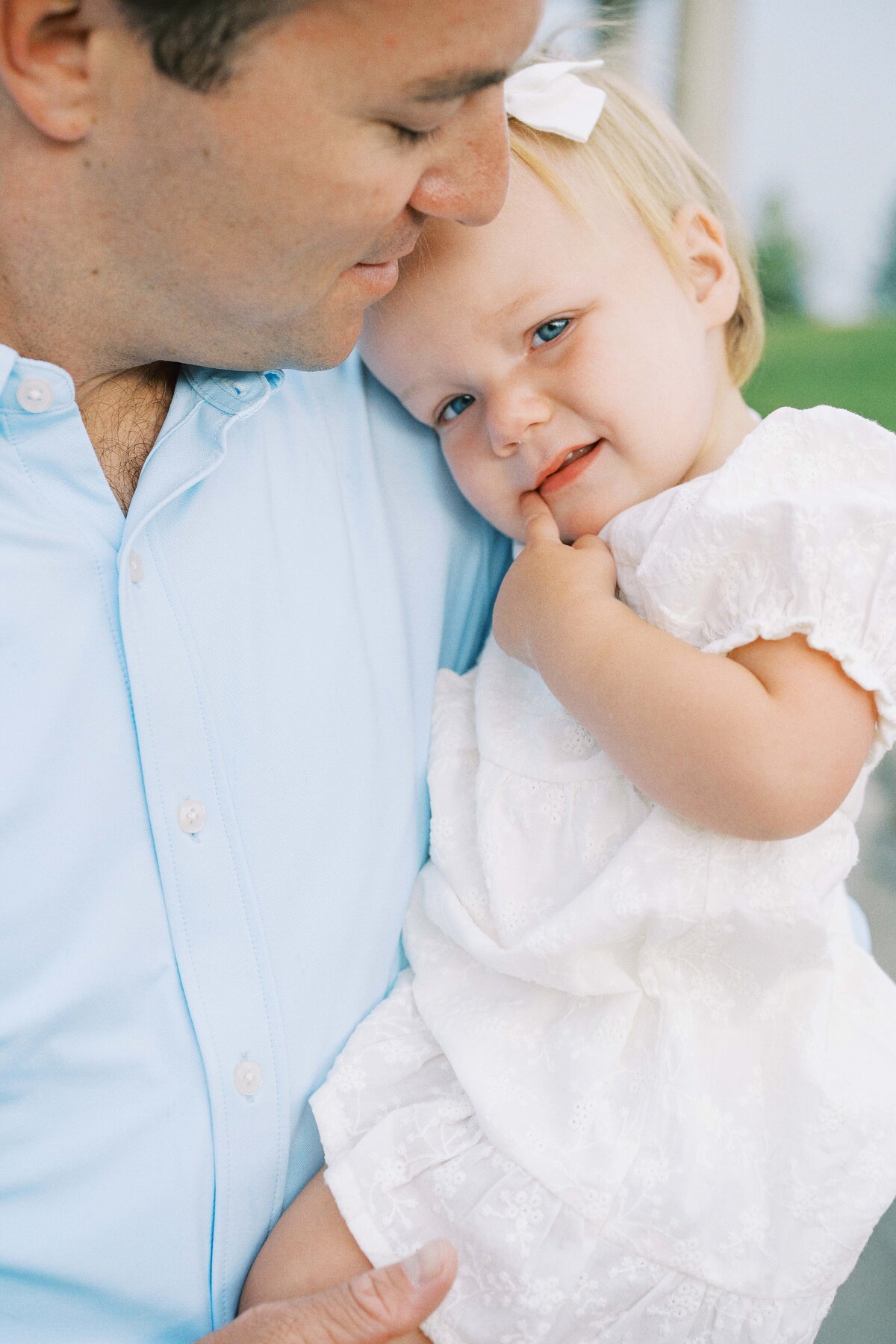 dad snuggling one year old daughter