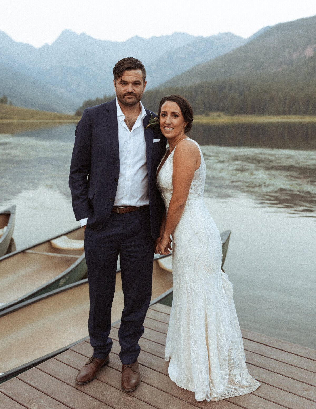 Bride and groom stand on the lake pier in the mountain on their wedding day at Piney River Ranch.