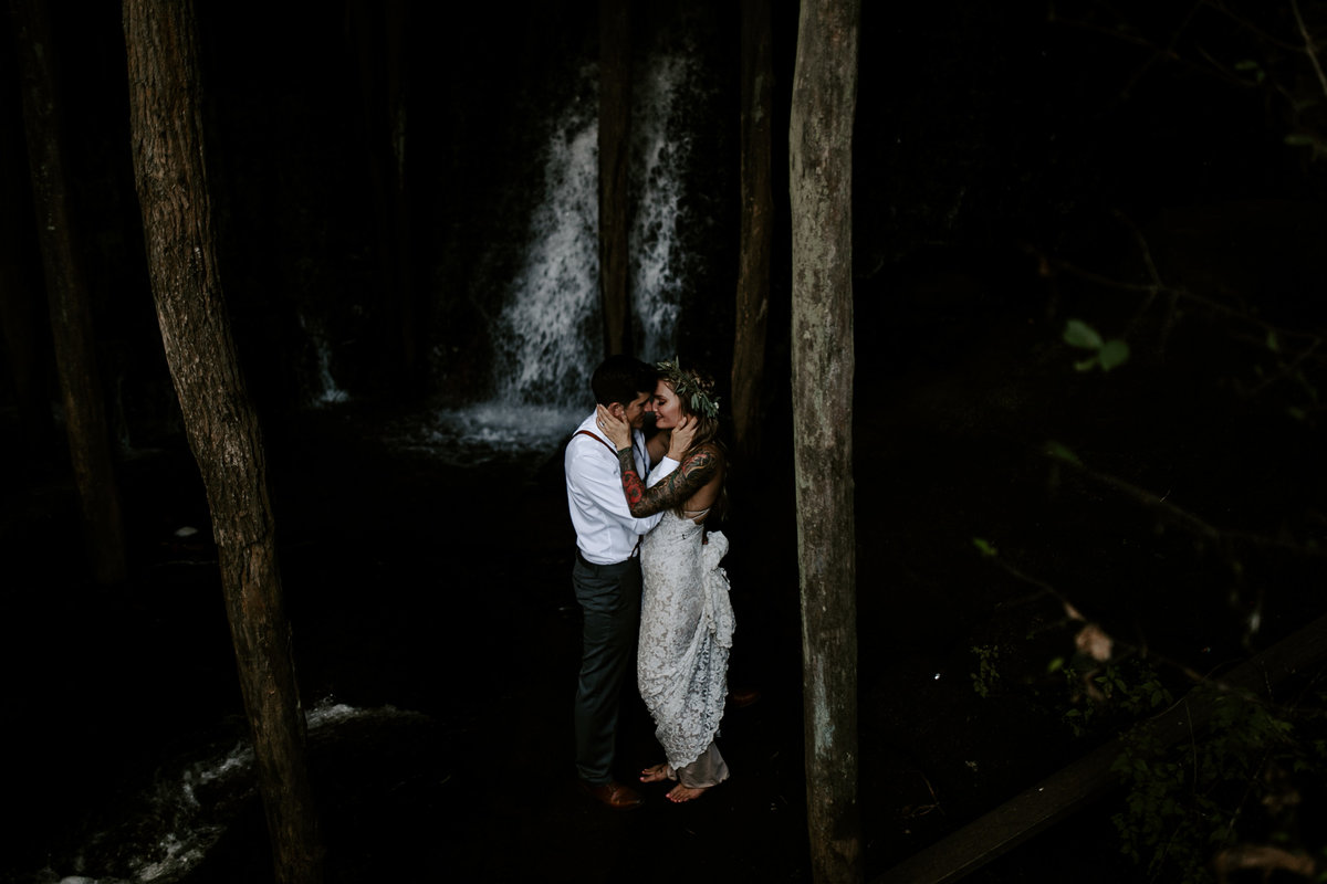bride and groom kissing in front of an Asheville waterfall
