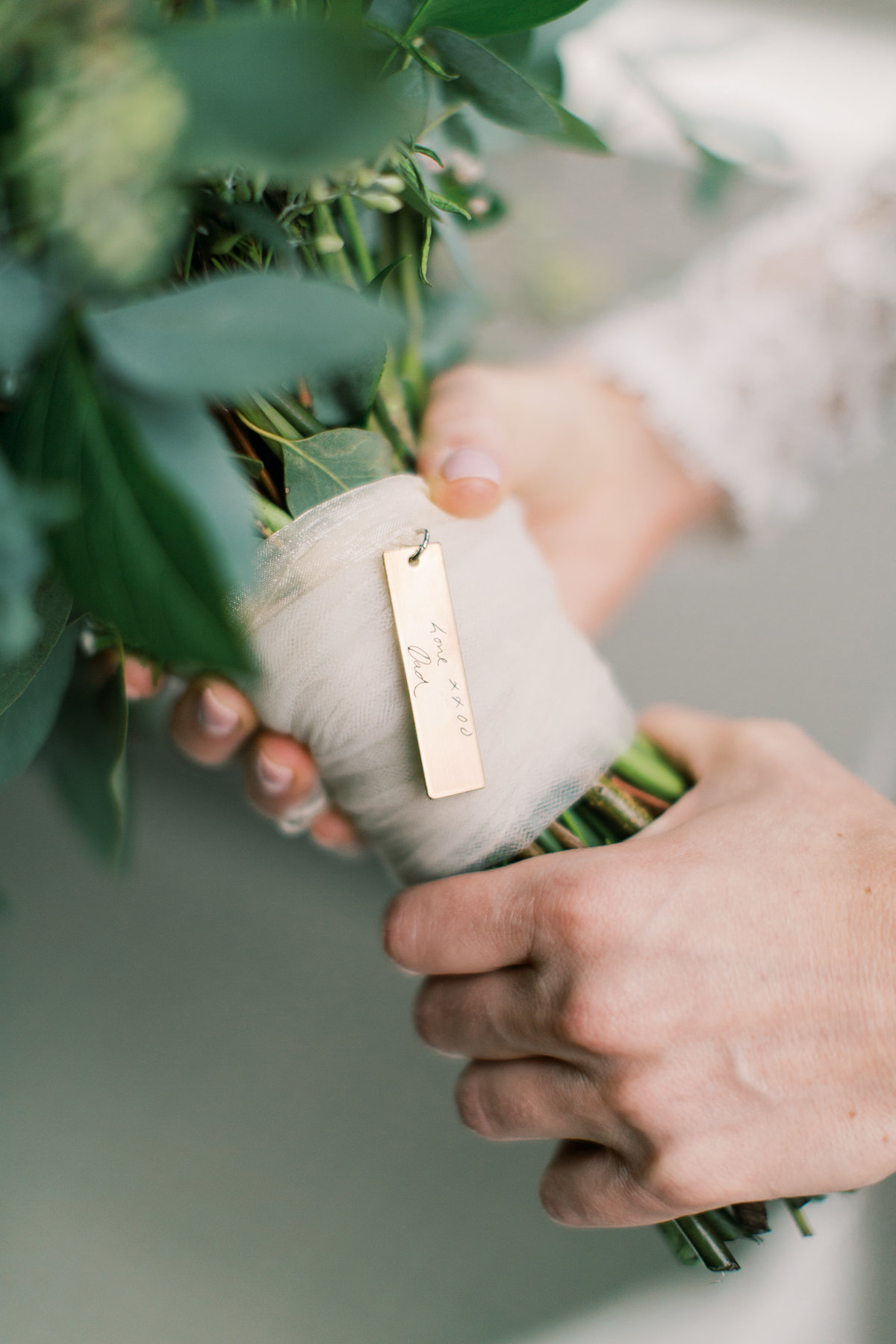 bride holding bridal bouquet with bouquet charm