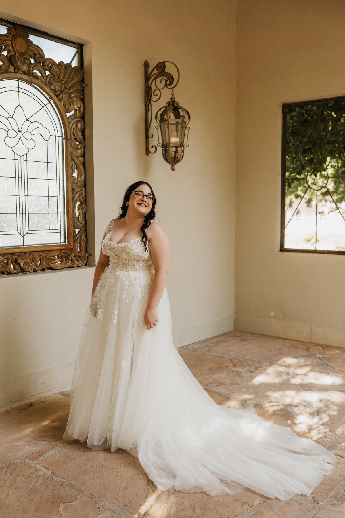 A person in a wedding dress standing in a garden patio smiling 