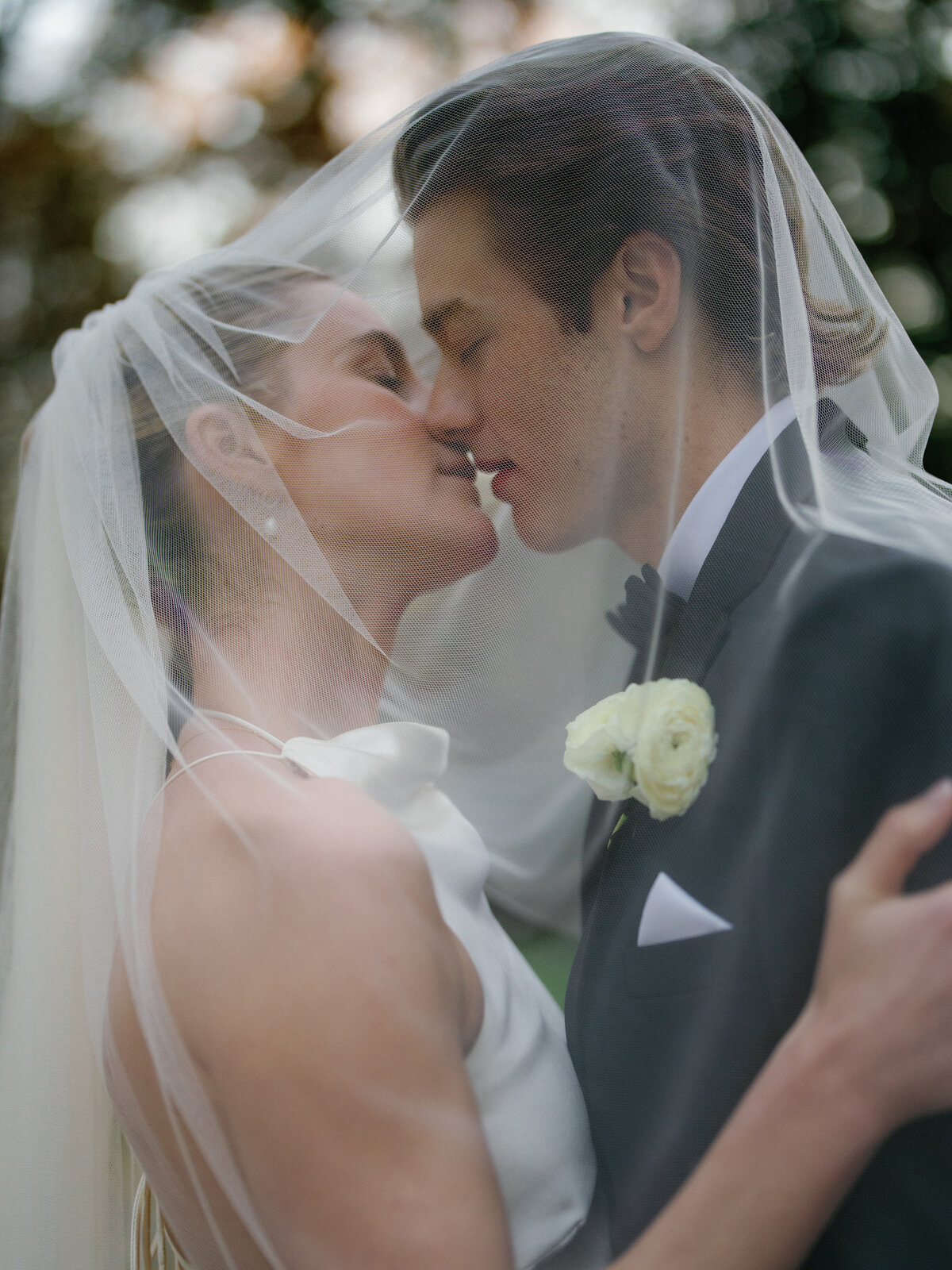 Bride and groom under veil sharing an intimate moment