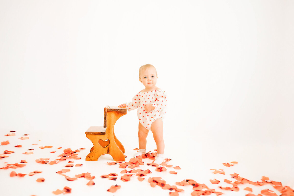 Springfield Mo kids photographer captures 1 year old birthday session of toddler girl smiling next to vintage wooden stool