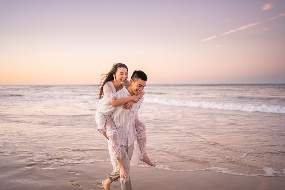 couple running on beach for their engagement photoshoot