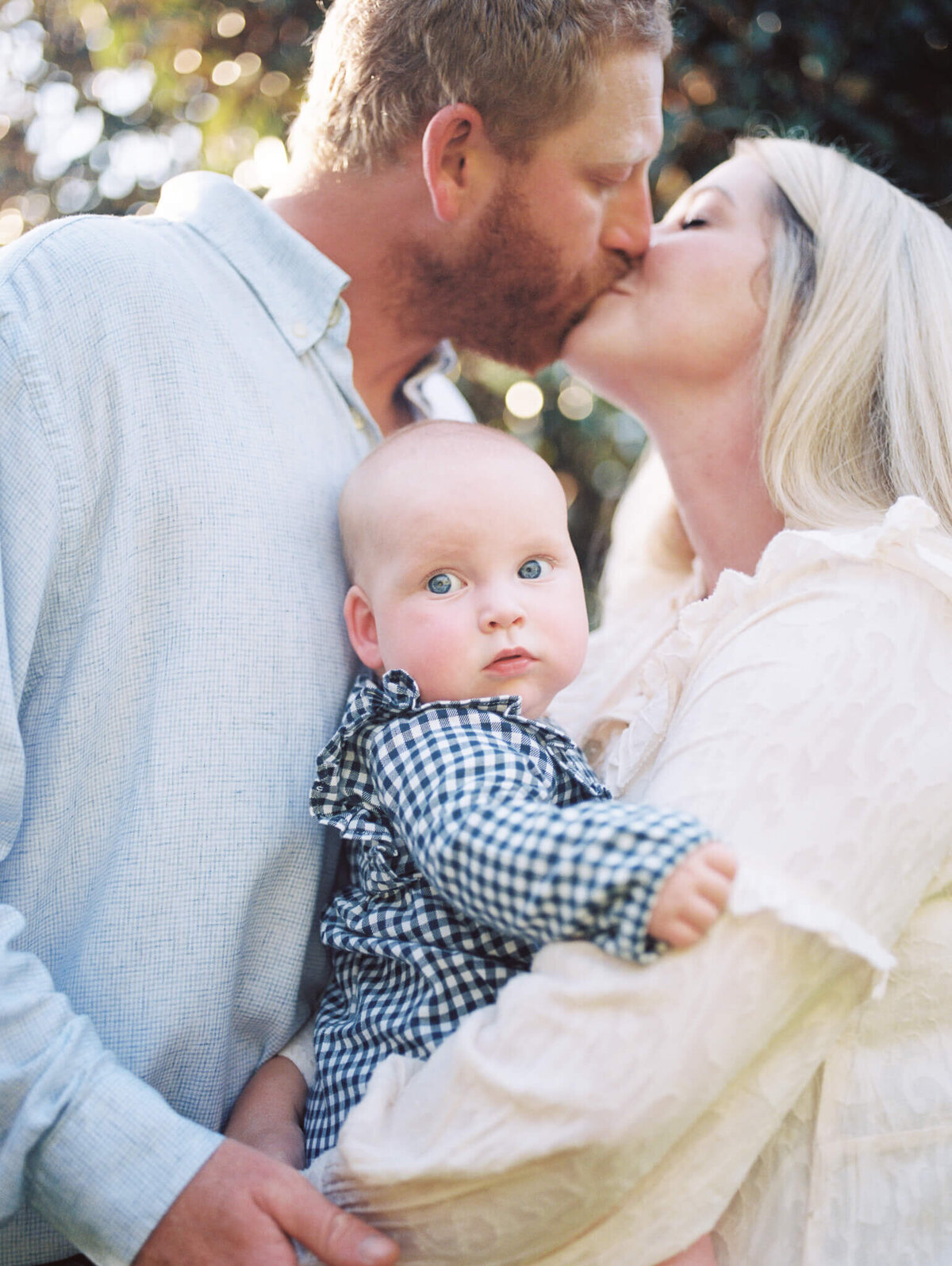 3 month old baby girl with parents kissing