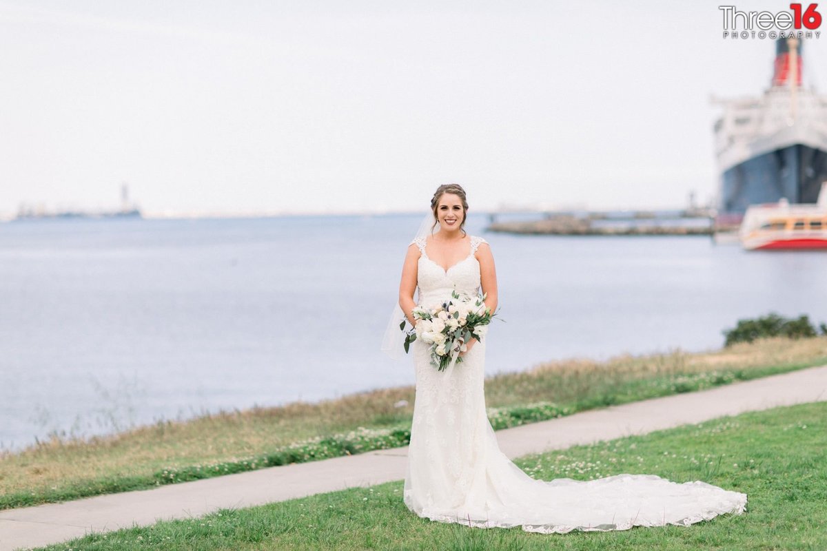 Bride poses for wedding photographer along the coast