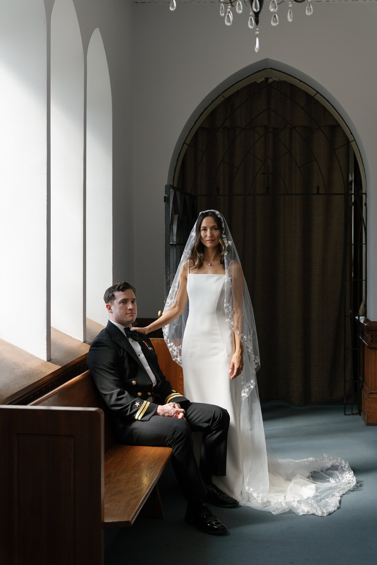 Bride and Groom posing on a bench inside church by film wedding photography