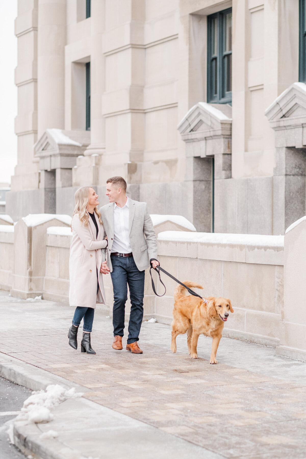 couple walking with their dog in the snow at Union Station during engagement session