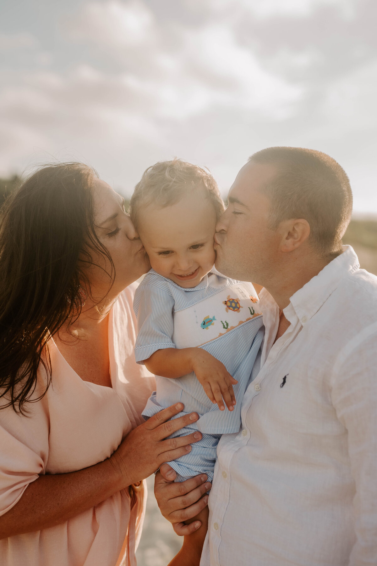 Mom and dad kiss son's cheeks