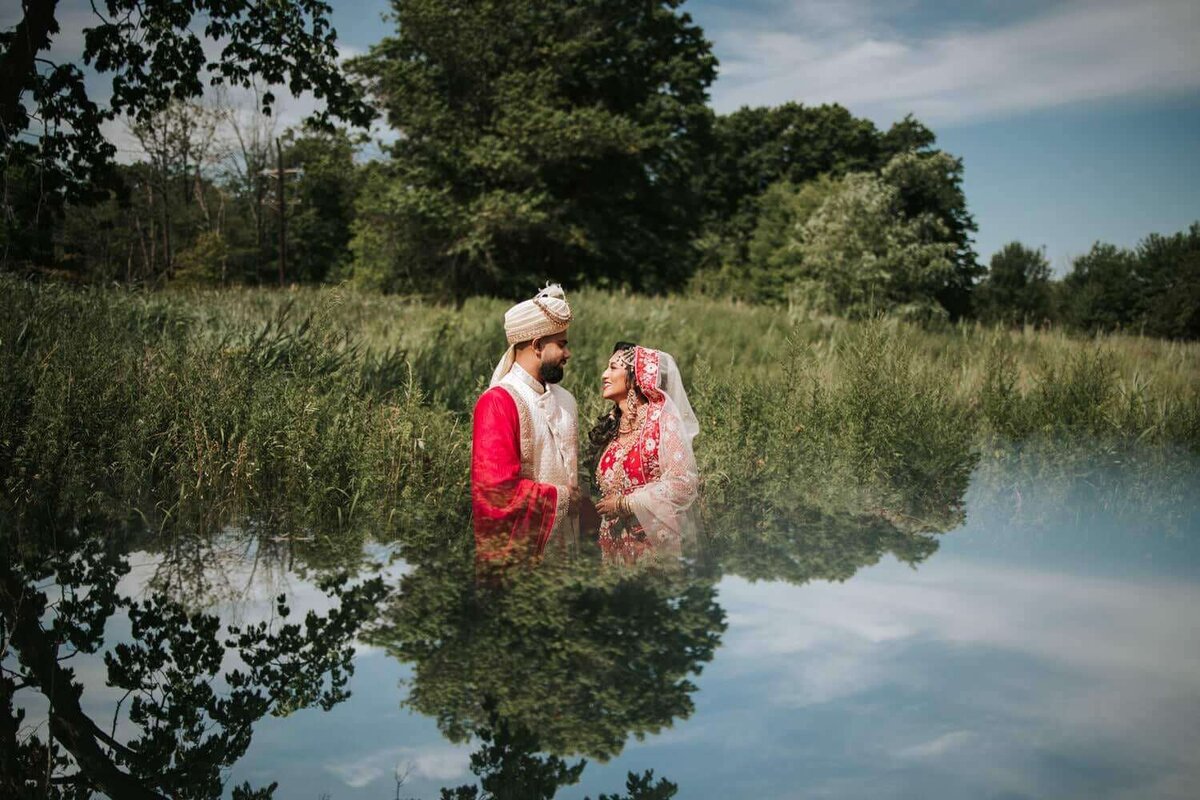 South Asian bride and groom standing in front of shrubbery sharing a moment of solitude after a long day of festivities in New Jersey.