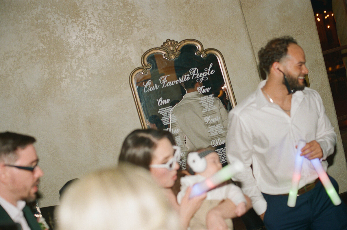 Large gold wood mirror with ornate arches at the top and calligraphy for a seating chart