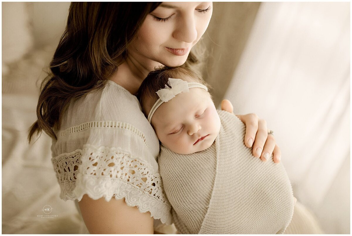 A mom hugging her swaddled baby girl