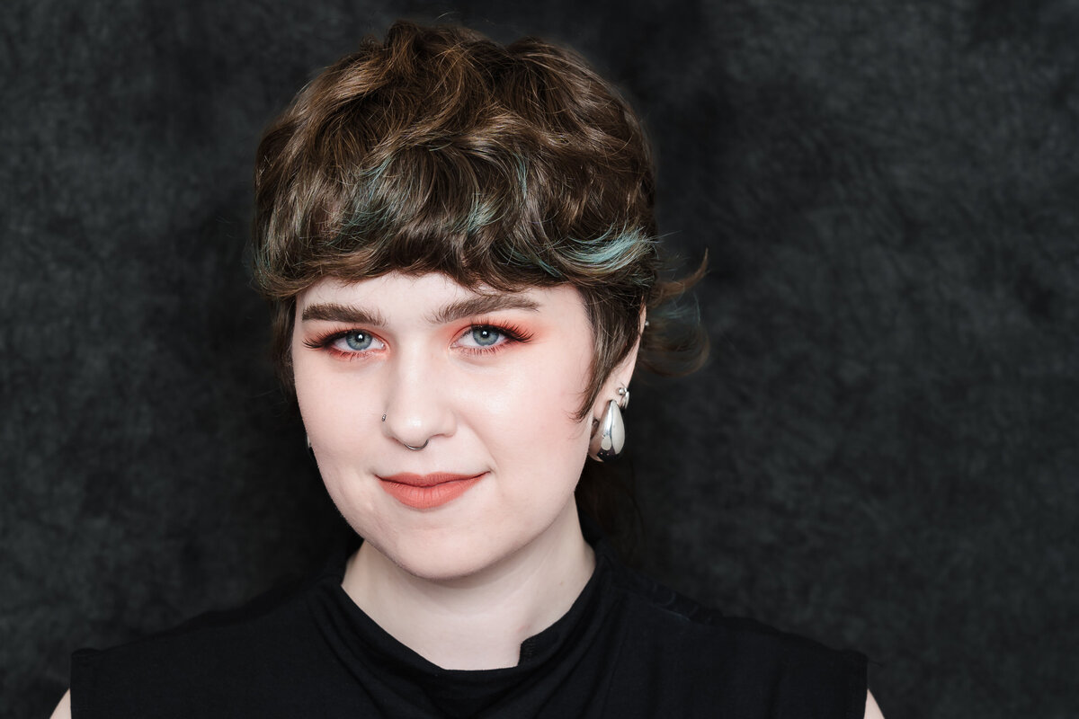 headshot of an artist wearing orange make up in her eyes