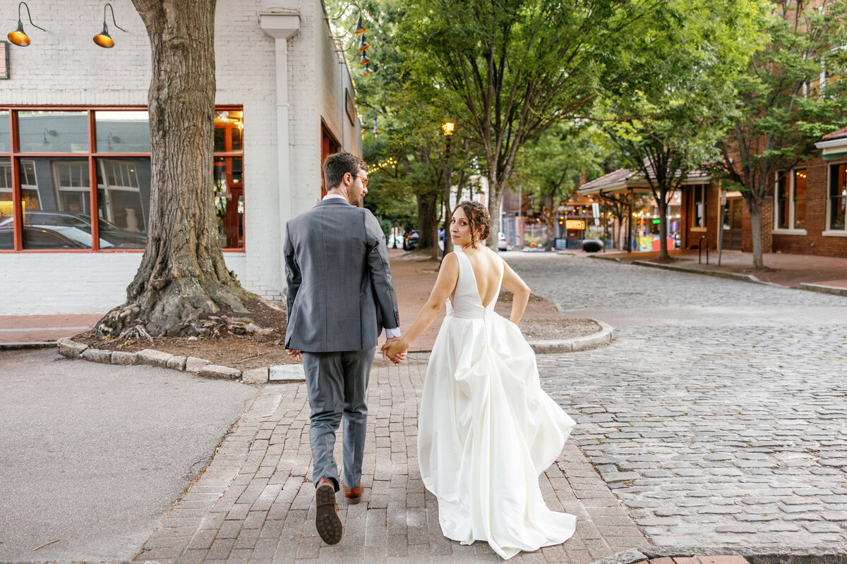 Bride and groom walking hand in hand on Raleigh street near Market Hall