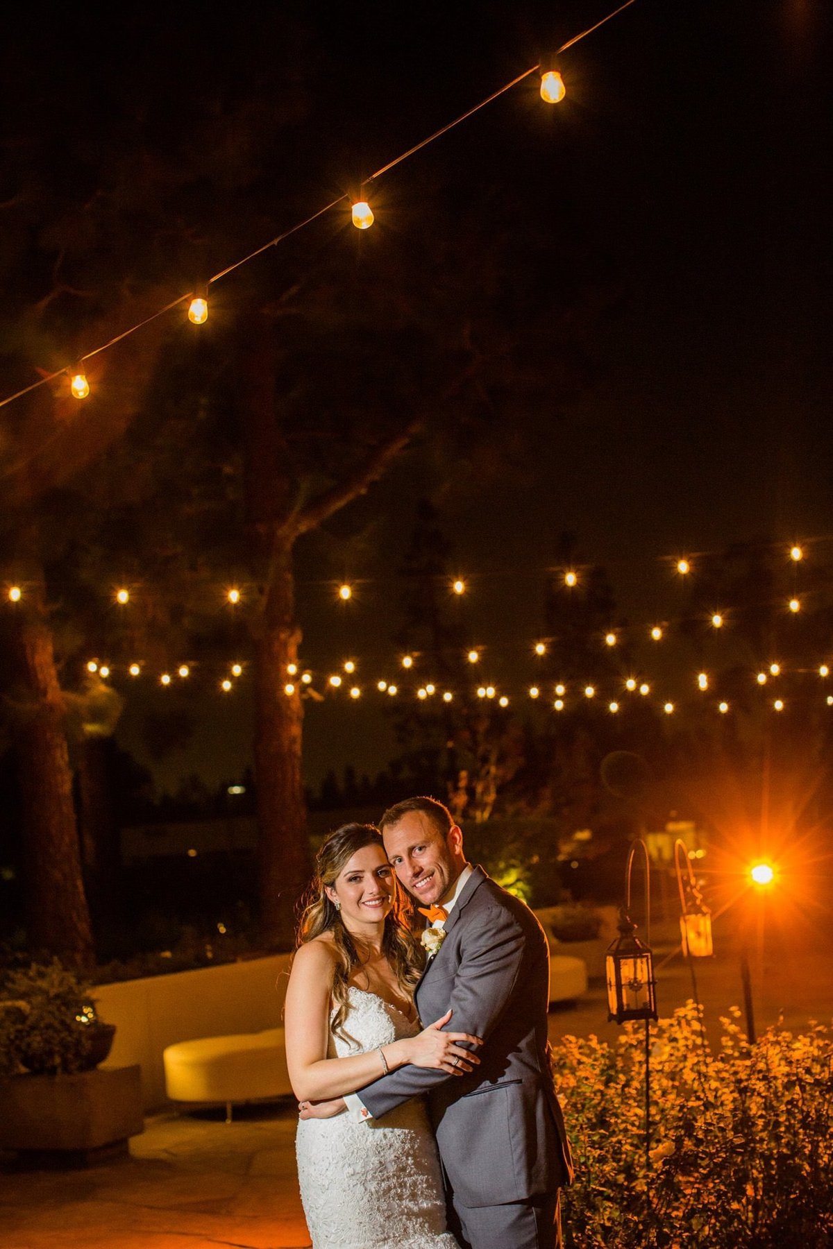 Bride and Groom pose cheek to cheek at night under the lights