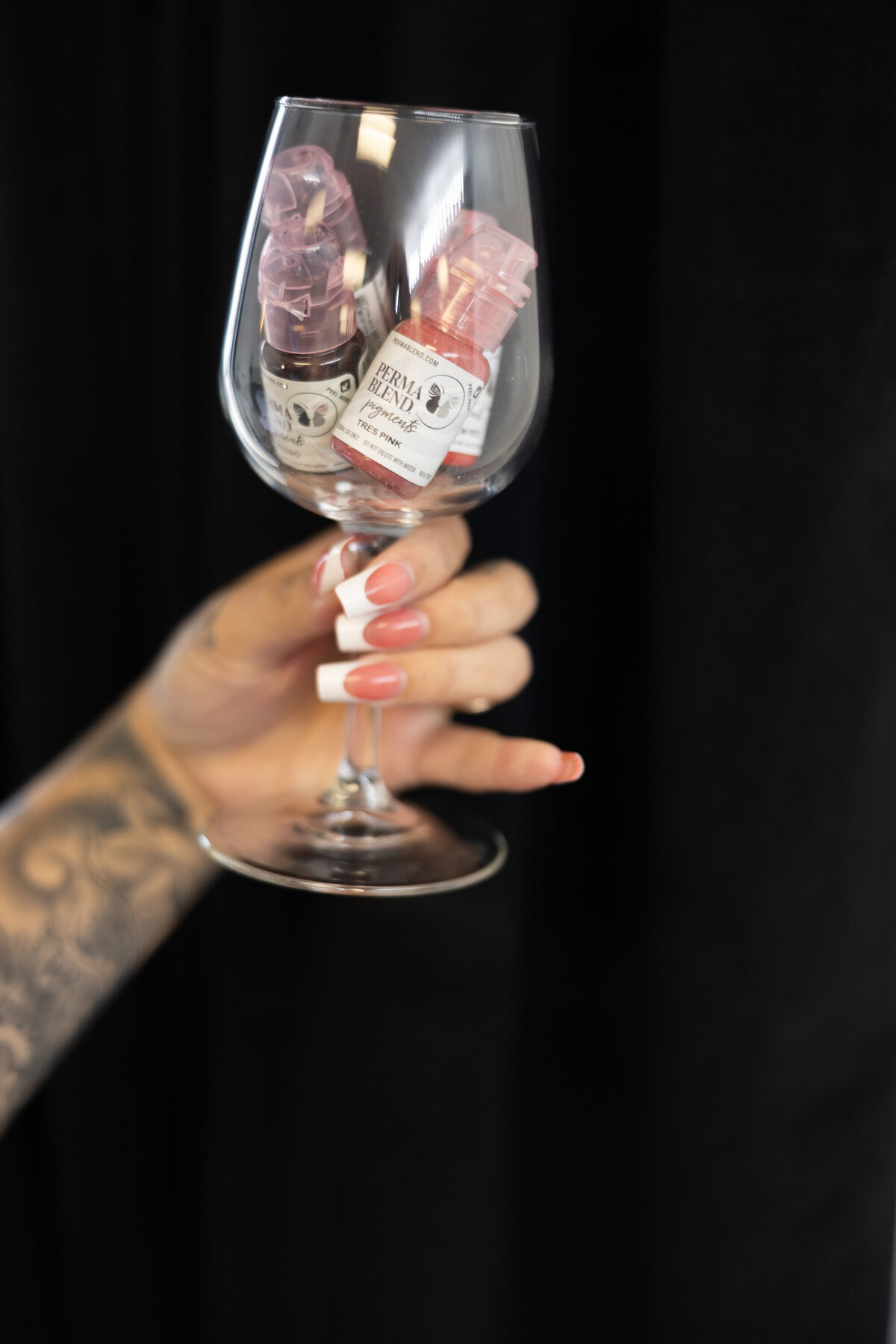 Close-up of tattooed hand holding decorative wine glass with floral design. Photograph by Yucaipa branding photographer Kaitlyn Dawn Photography.