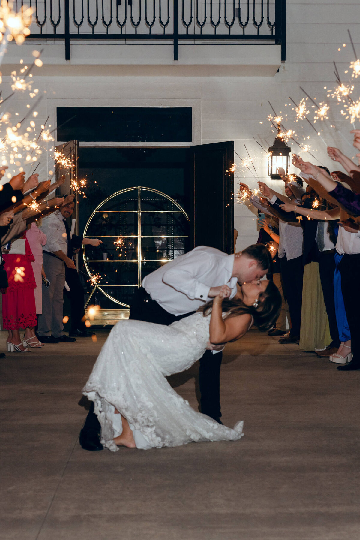 A wedding photo of the bride and groom doing a dip kiss during their wedding exit