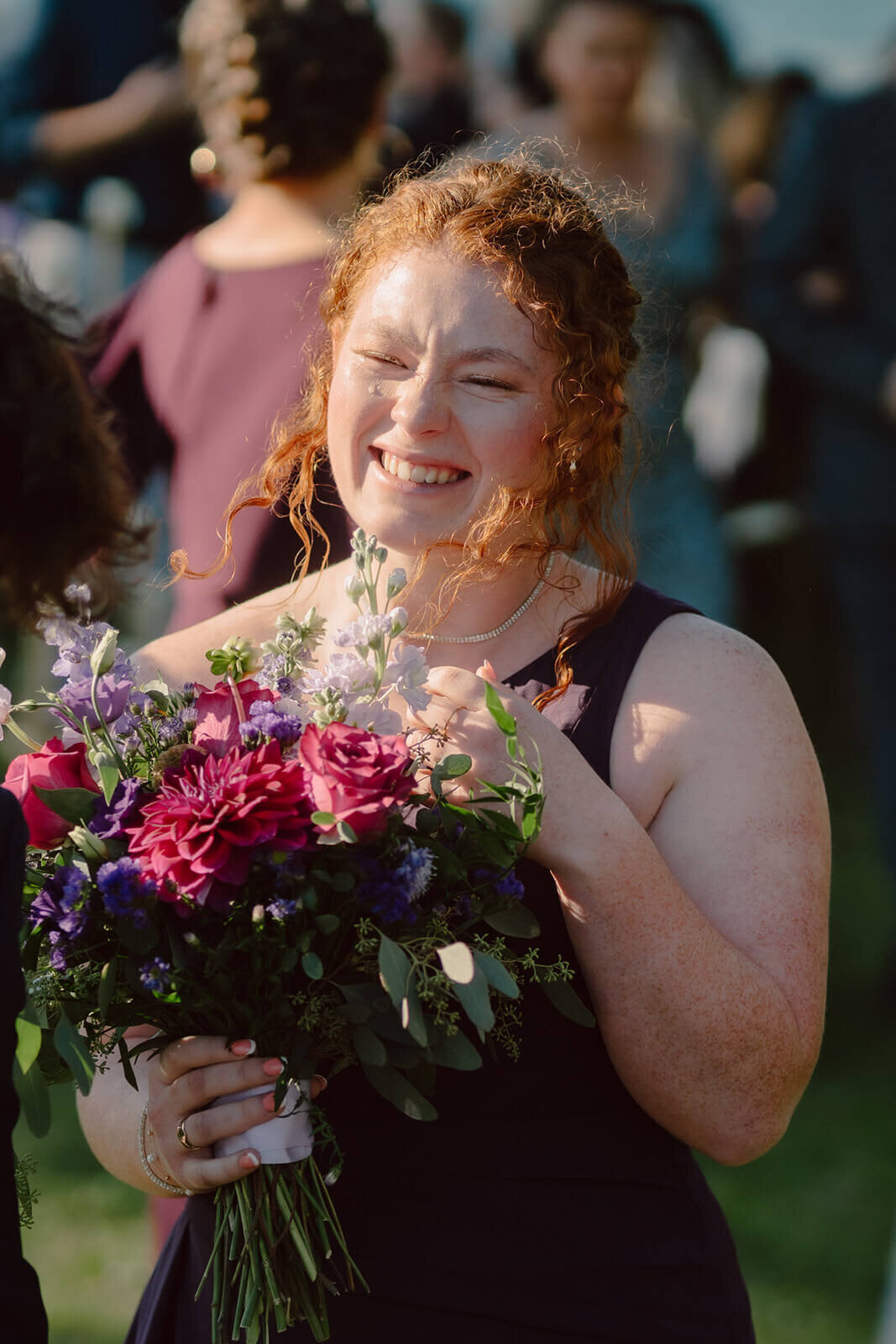 Bridesmaids holding large bouquet and smiling at Finger Lakes wedding