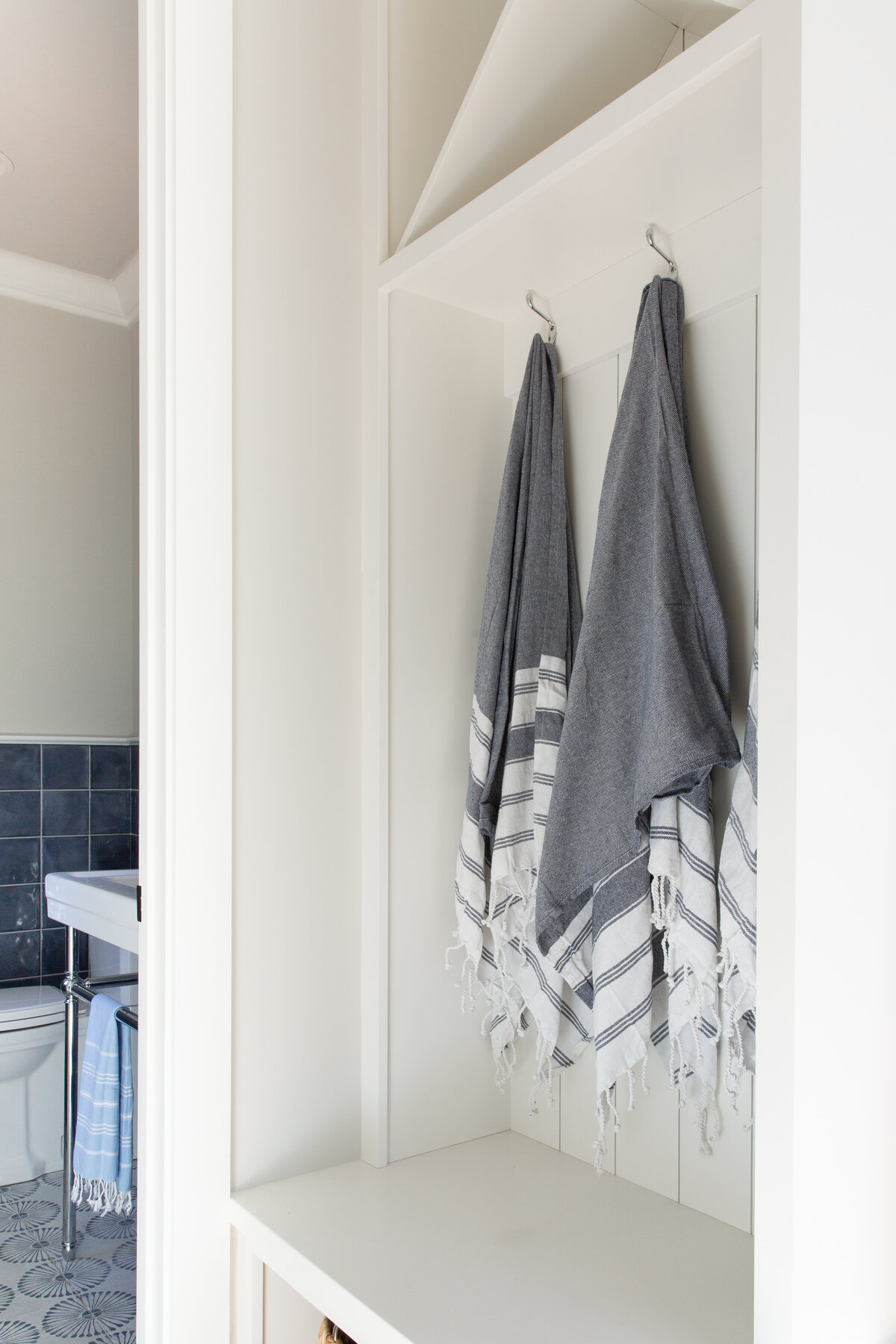 Stylish bathroom in Kiawah Island, SC, with hanging Turkish towels and a glimpse of blue tile accents.