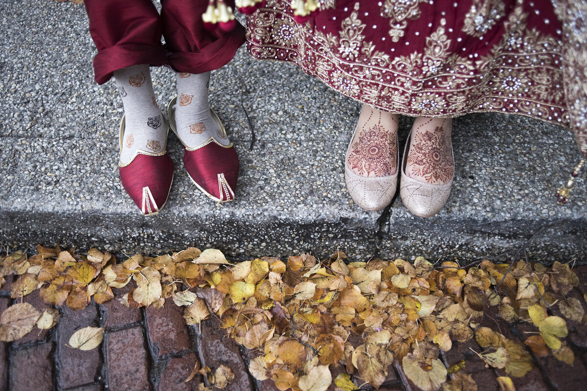 View looking down at two sets of feed with colorful shoes and henna tattoos 