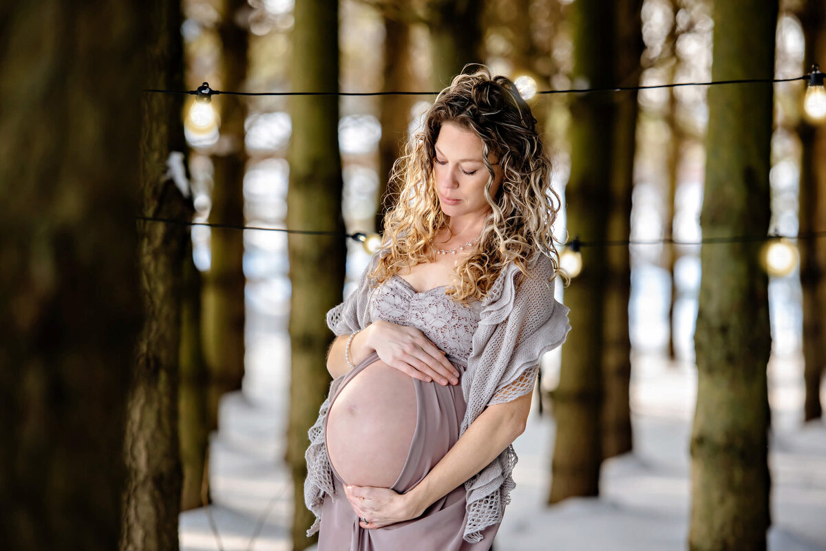 Blonde pregnant woman holding her belly in her outdoor winter maternity photography session