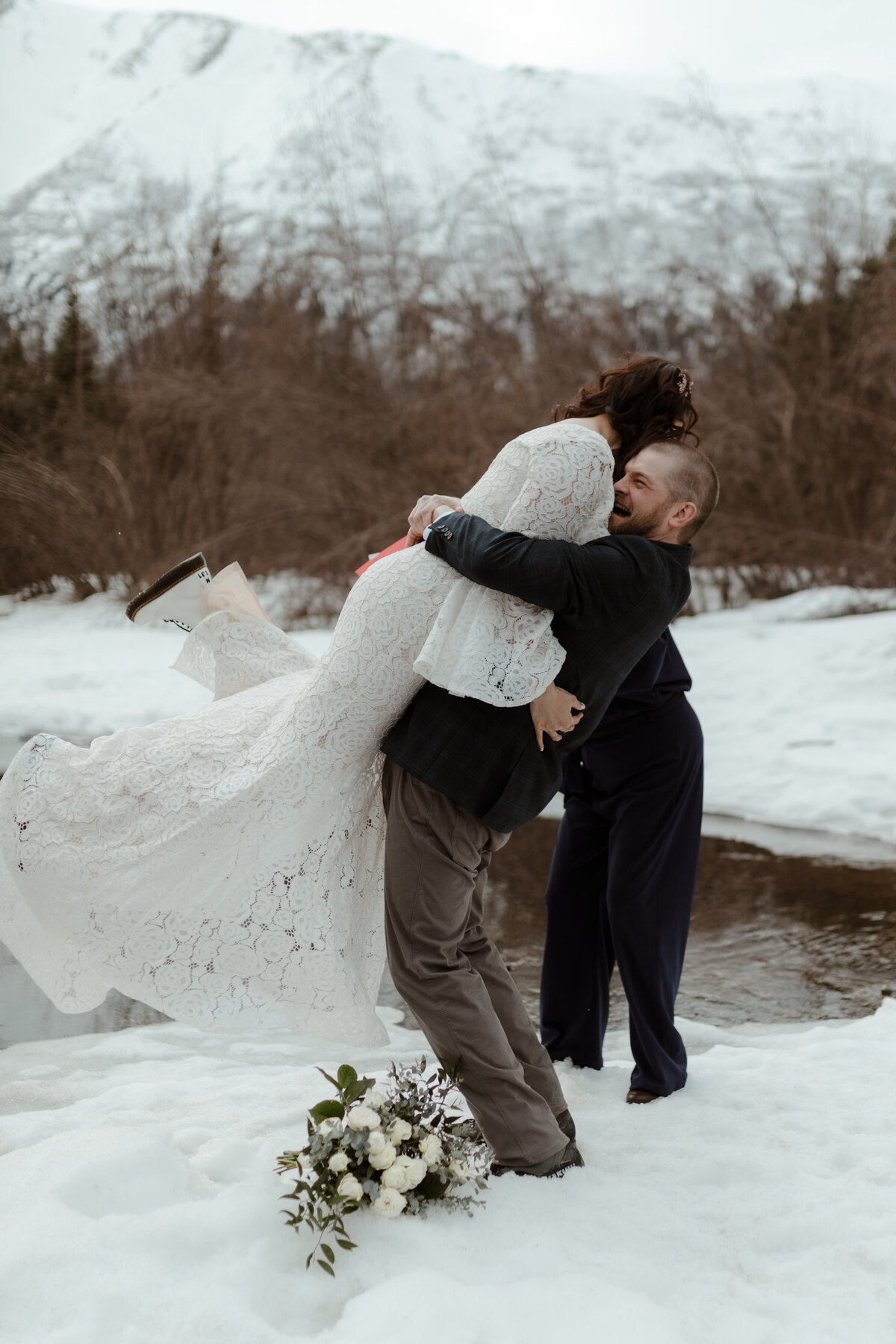 bride and groom embracing by river