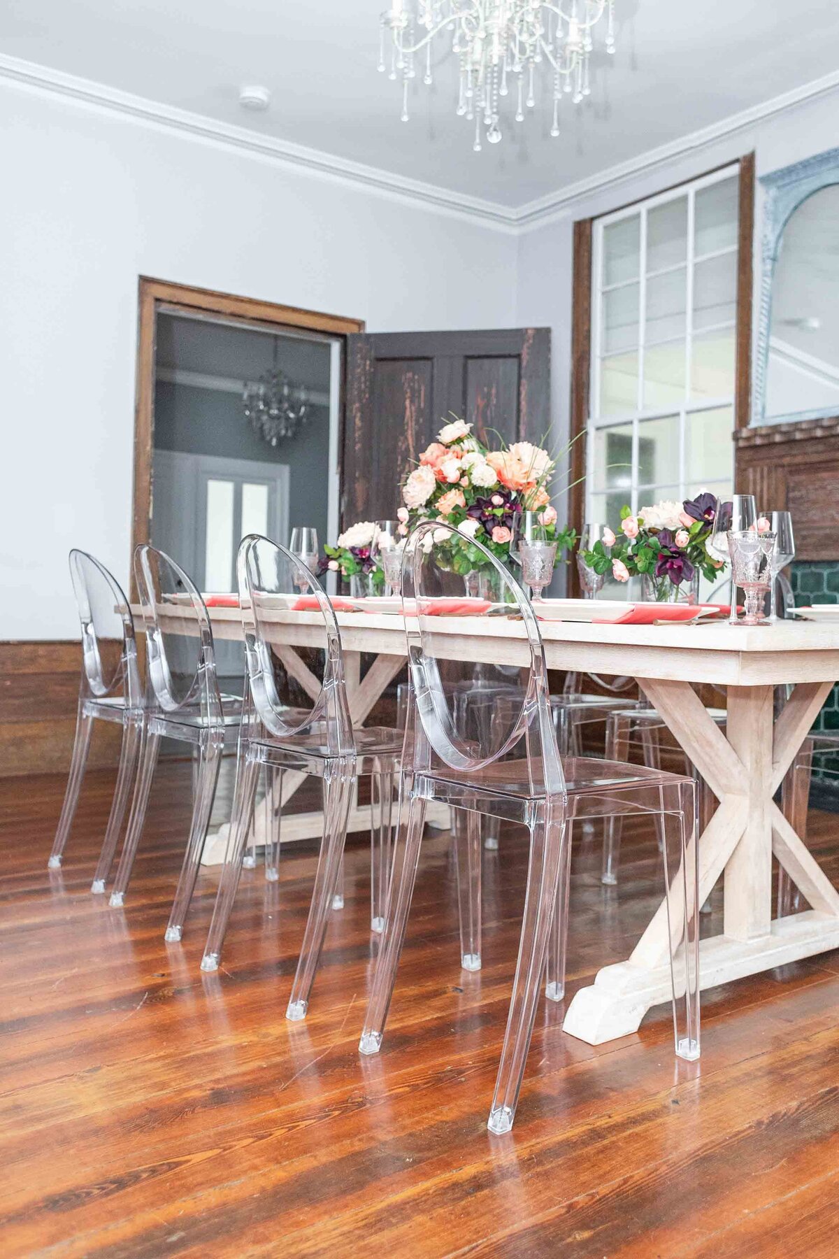 n a unique setting, an event expert has beautifully decorated a table with peach flowers, elegant plates, and cutlery. The backdrop features a large wooden door, adding a rustic charm to the setup.