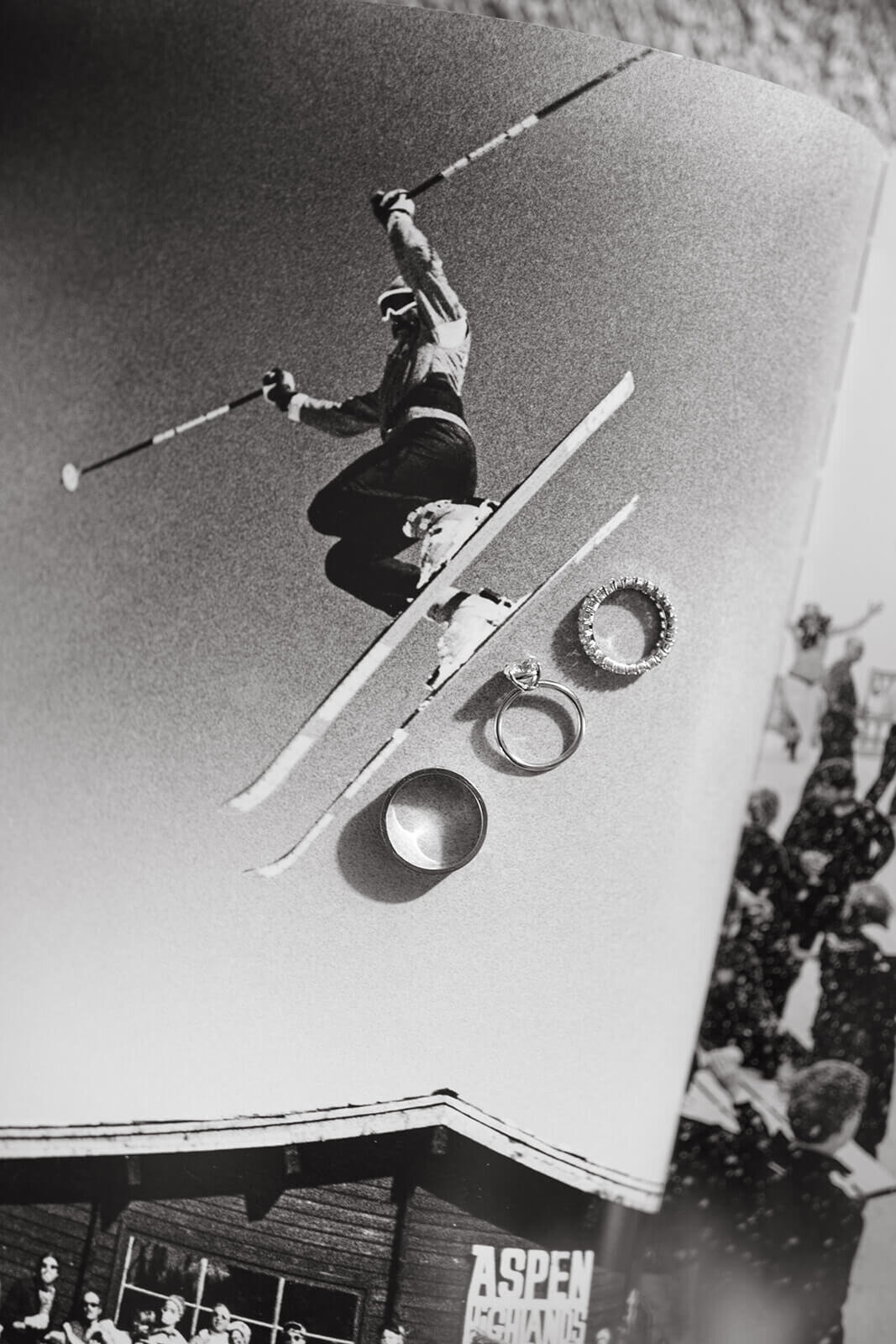 Wedding rings displayed on a vintage photo backdrop of a skier at St. Regis Aspen, showcasing elegant details.
