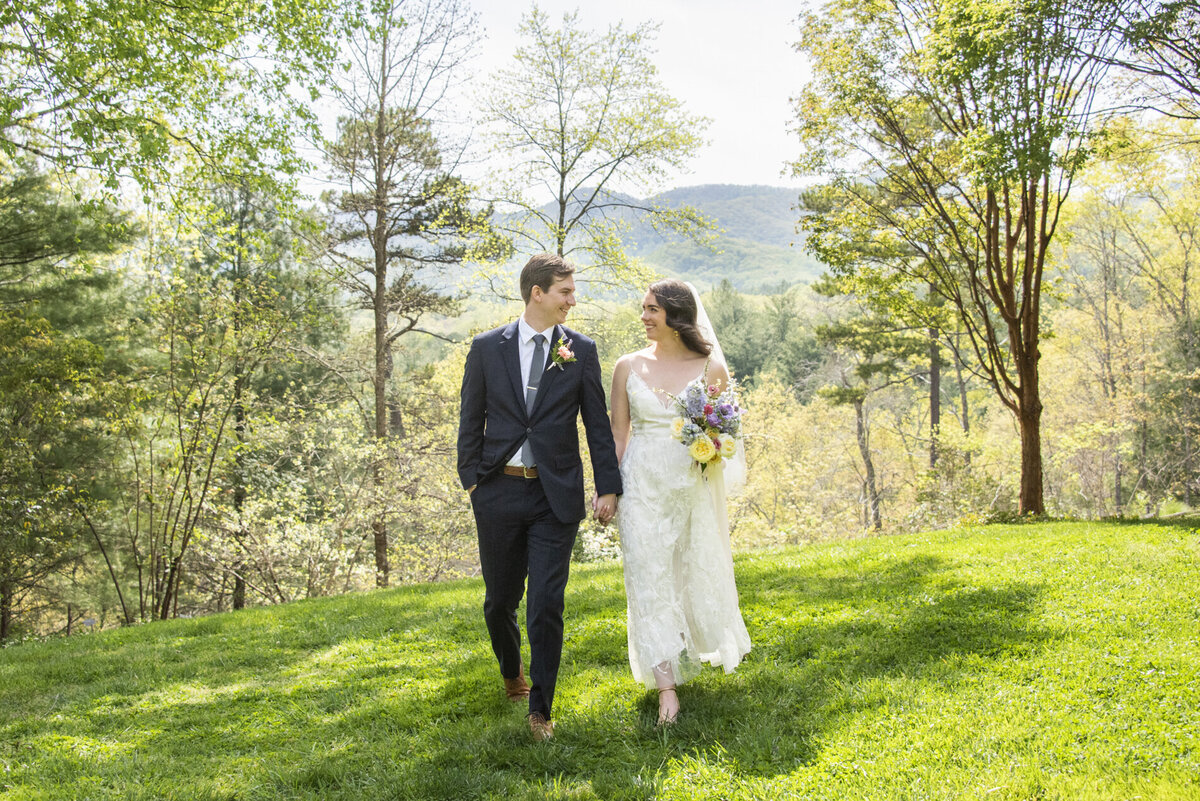 Couple walking with mountains behind at NC Arboretum wedding