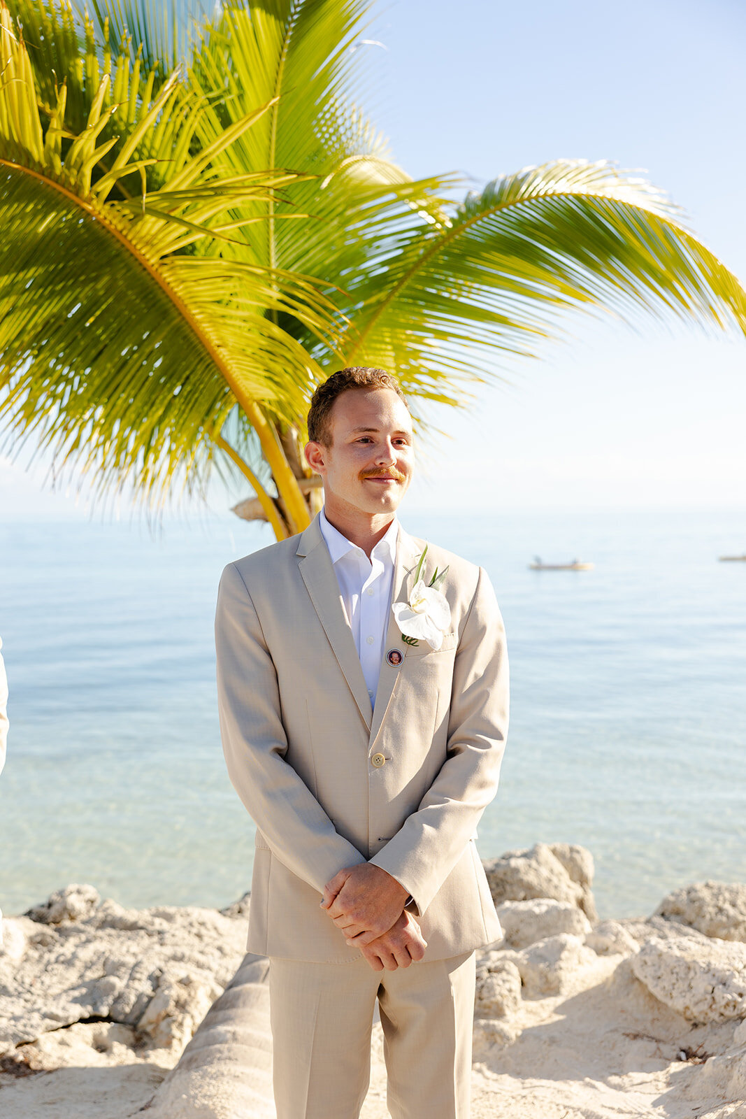 Hunter stands by the ocean in a beige suit, looking emotional before the ceremony.