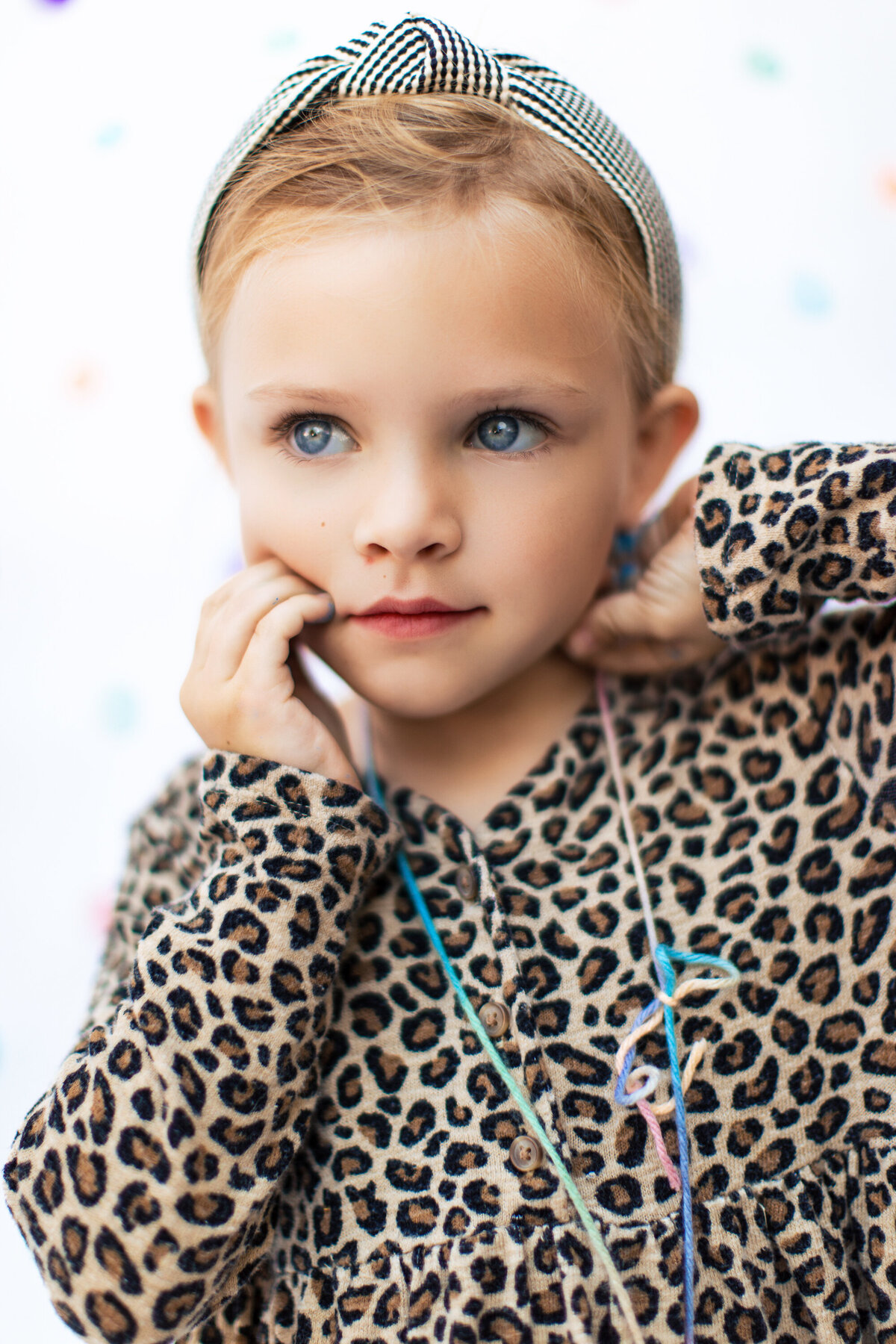 Blonde girl with striking eyes in a stylish top looks often to the distance during a children's photography shoot