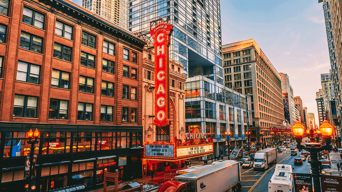 A classic illuminated marquee of the Chicago Theatre stands tall against the night sky, with its bold red and gold design glowing warmly. This iconic landmark showcases the vibrant cultural and entertainment experiences supported by vacation fundraising for charities.