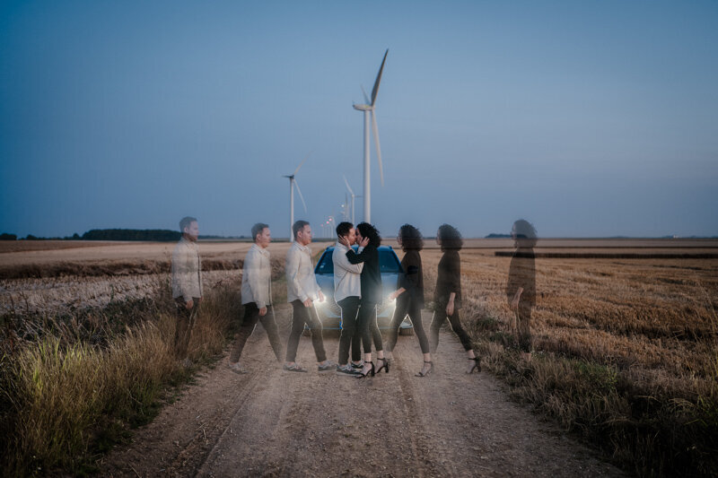 Photo de couple créative réalisée dans un parc éolien, avec un effet de double exposition en postproduction sur Photoshop, pour une ambiance cinématographique et symbolique.