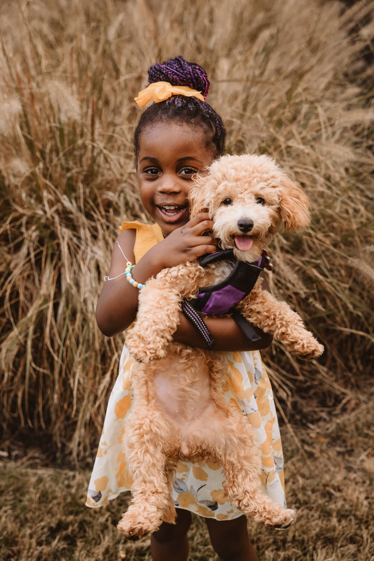 A child smiling as they hold a dog 