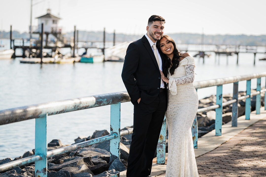 Engaged couple smiling by the Perth Amboy waterfront in New Jersey, photographed by Alex Kaplan Photography.