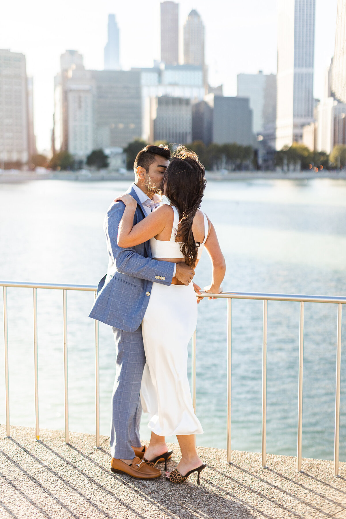 Couple embracing by a waterfront with a city skyline in the background