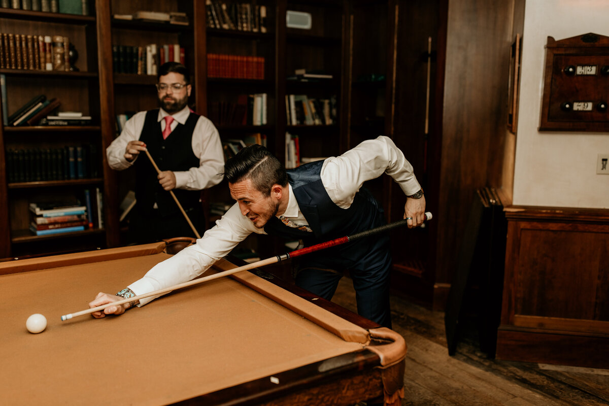 groom playing pool with buddies before wedding ceremony