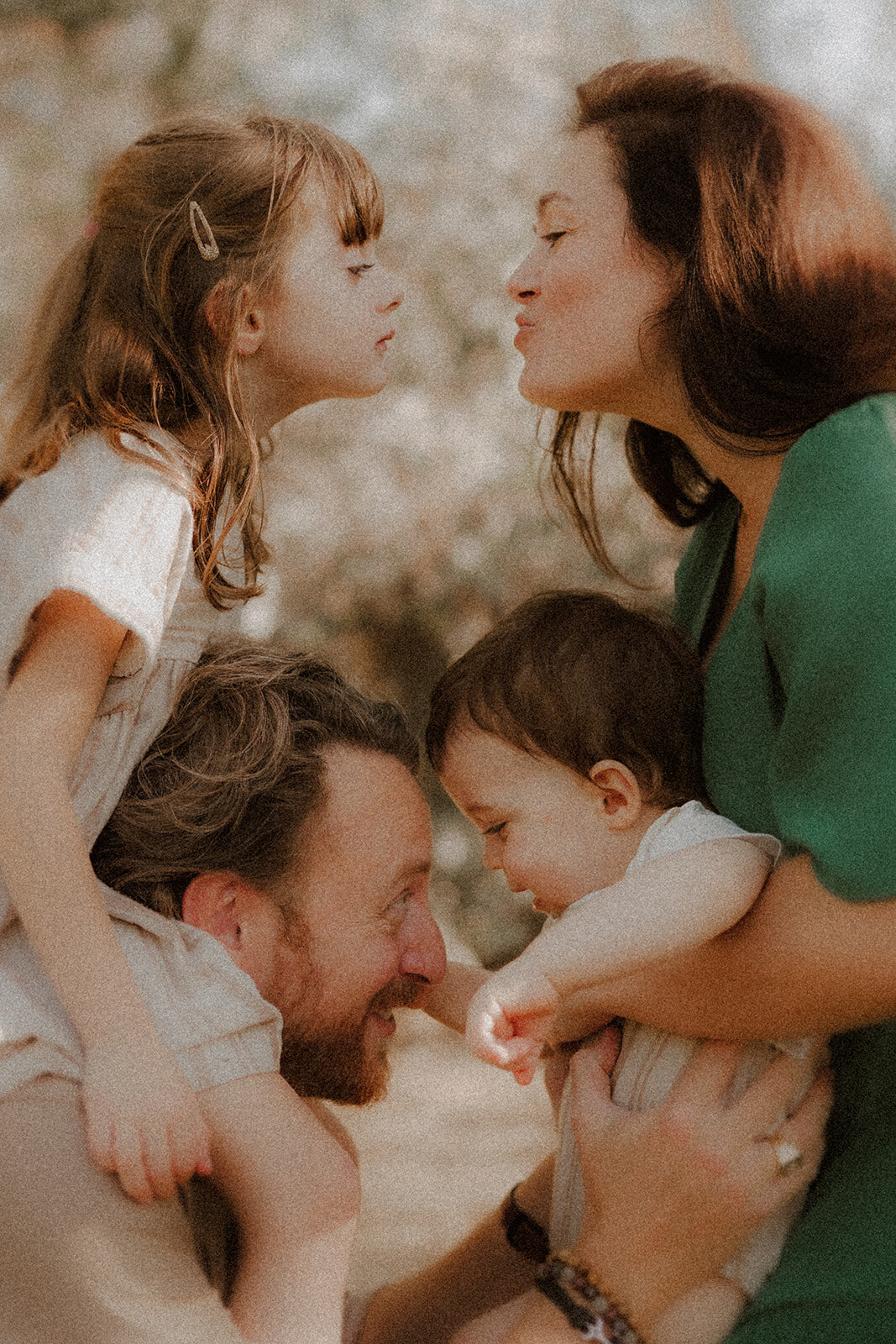 photo famille petite fille sur les epaules de son papa embrasse sa maman qui tient bebe dans les bras en foret cannes alpes-maritimes