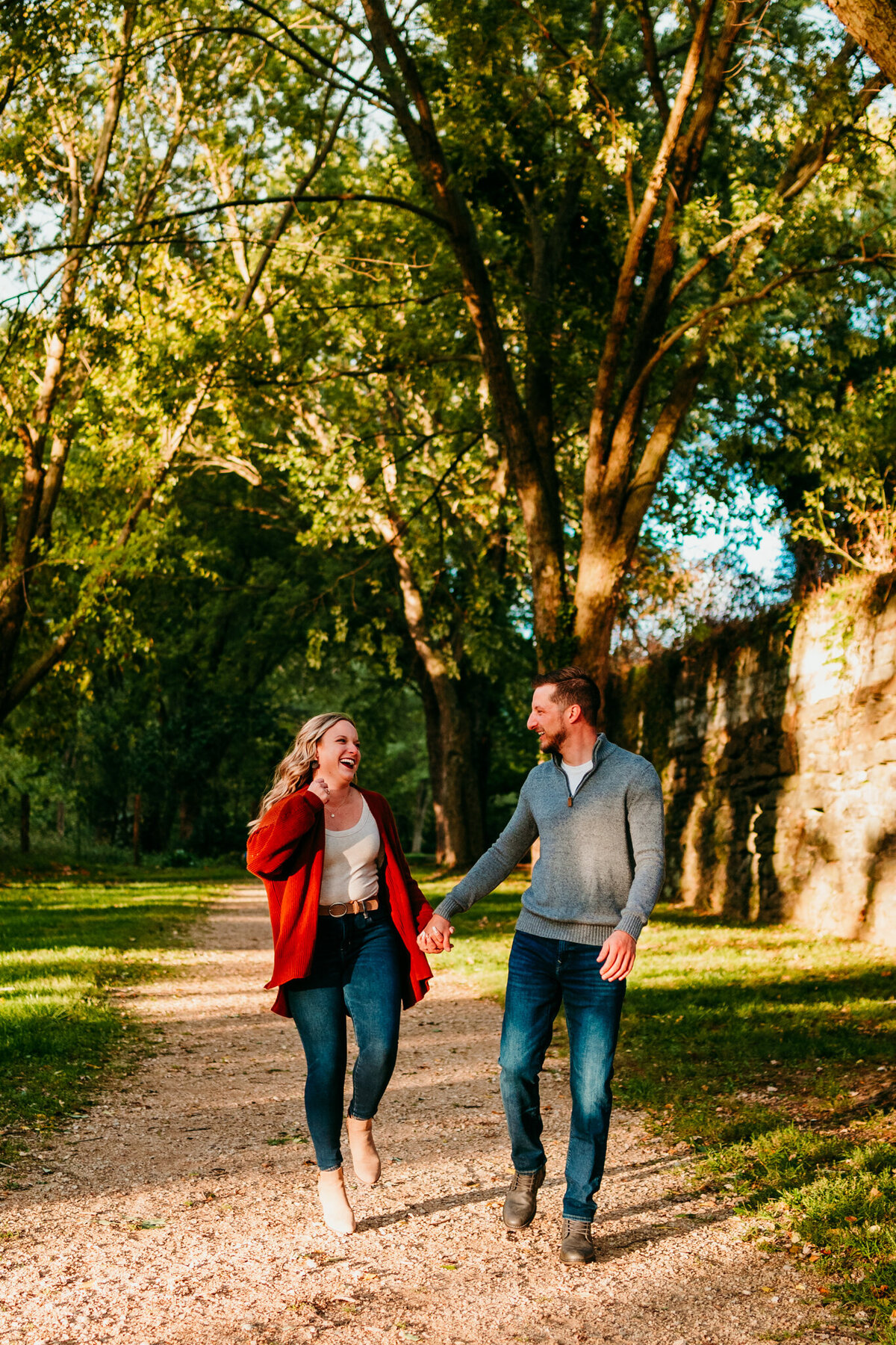  Couple walking hand-in-hand down a forest trail during golden hour