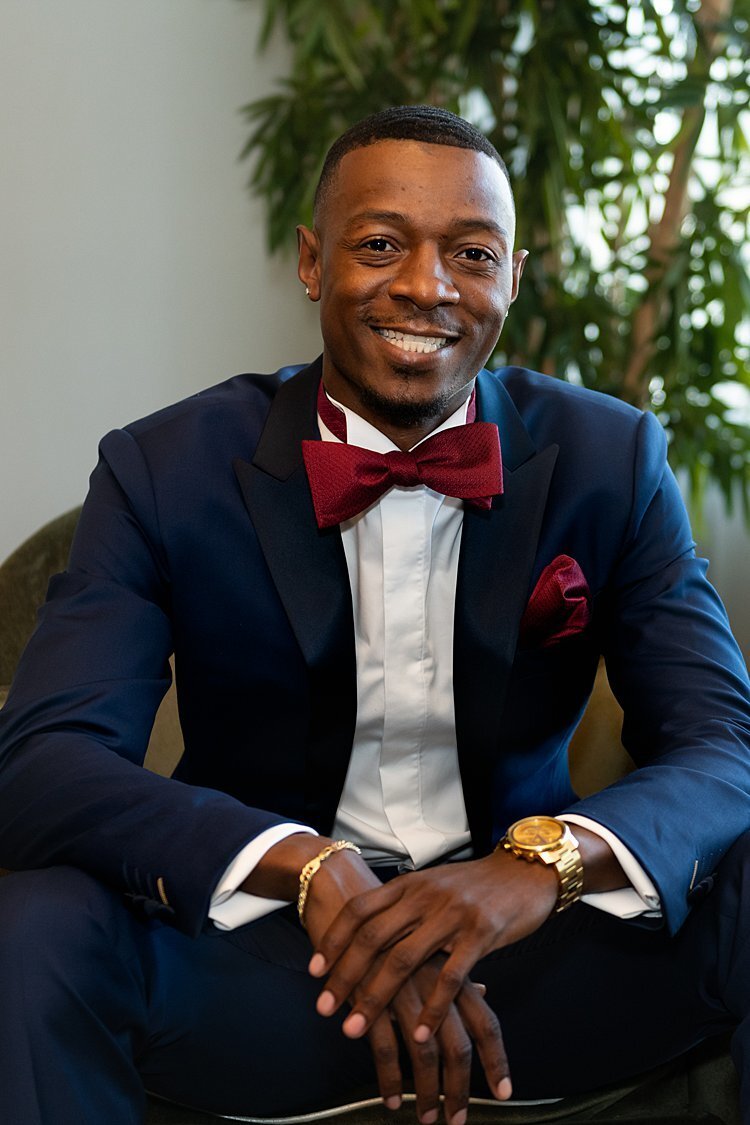 Portrait of Stylish Groom wearing navy suit and burgundy bowtie and pocket square