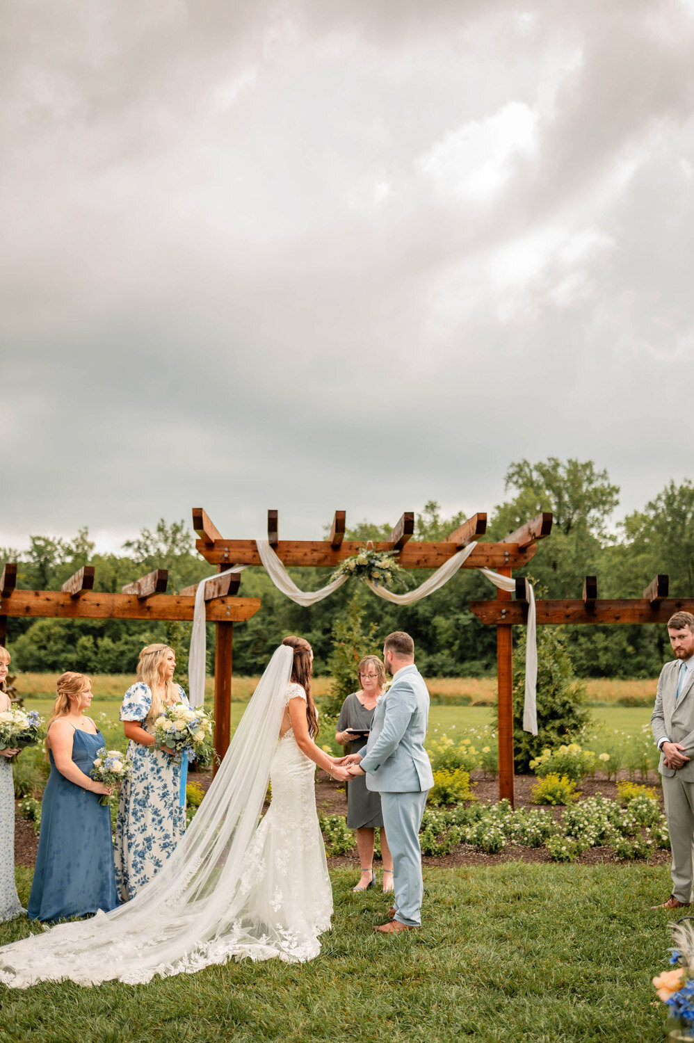 Wedding ceremony under the pergola with bride, groom, officiant, and bridesmaids
