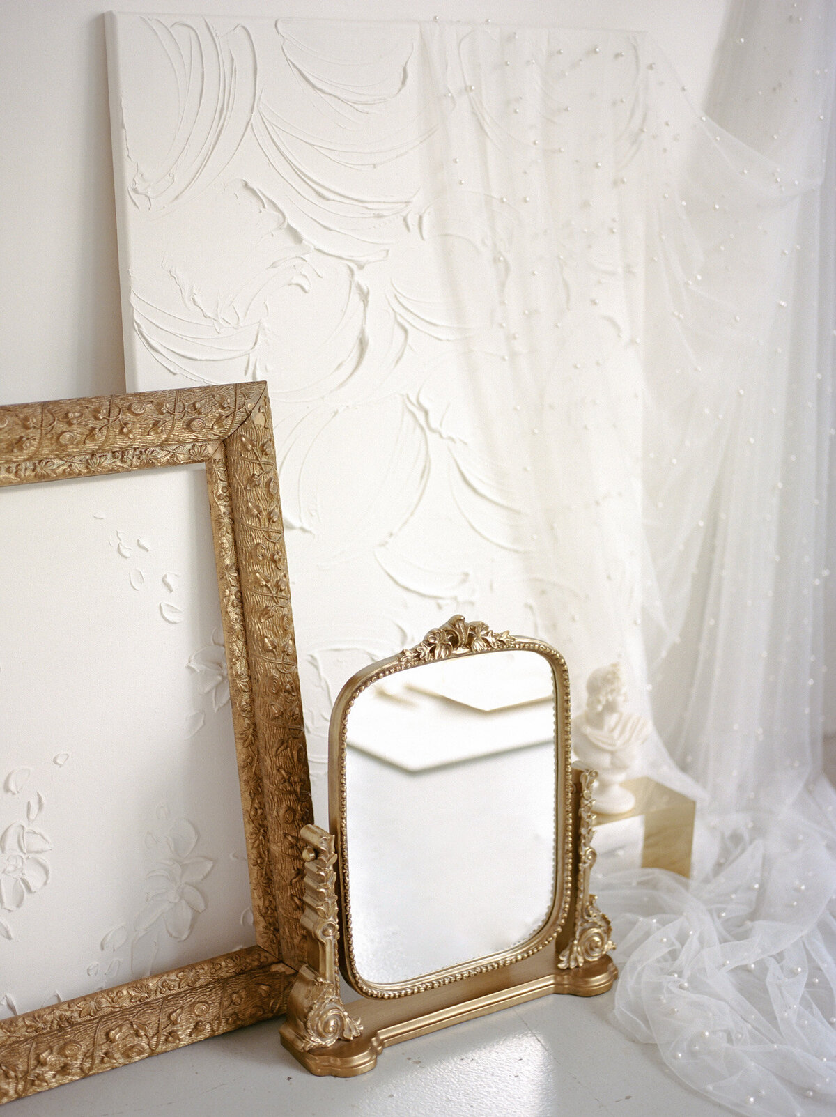 glimmering gold anthropologie mirror, textured background, bust sculpture candle for florist brand photoshoot