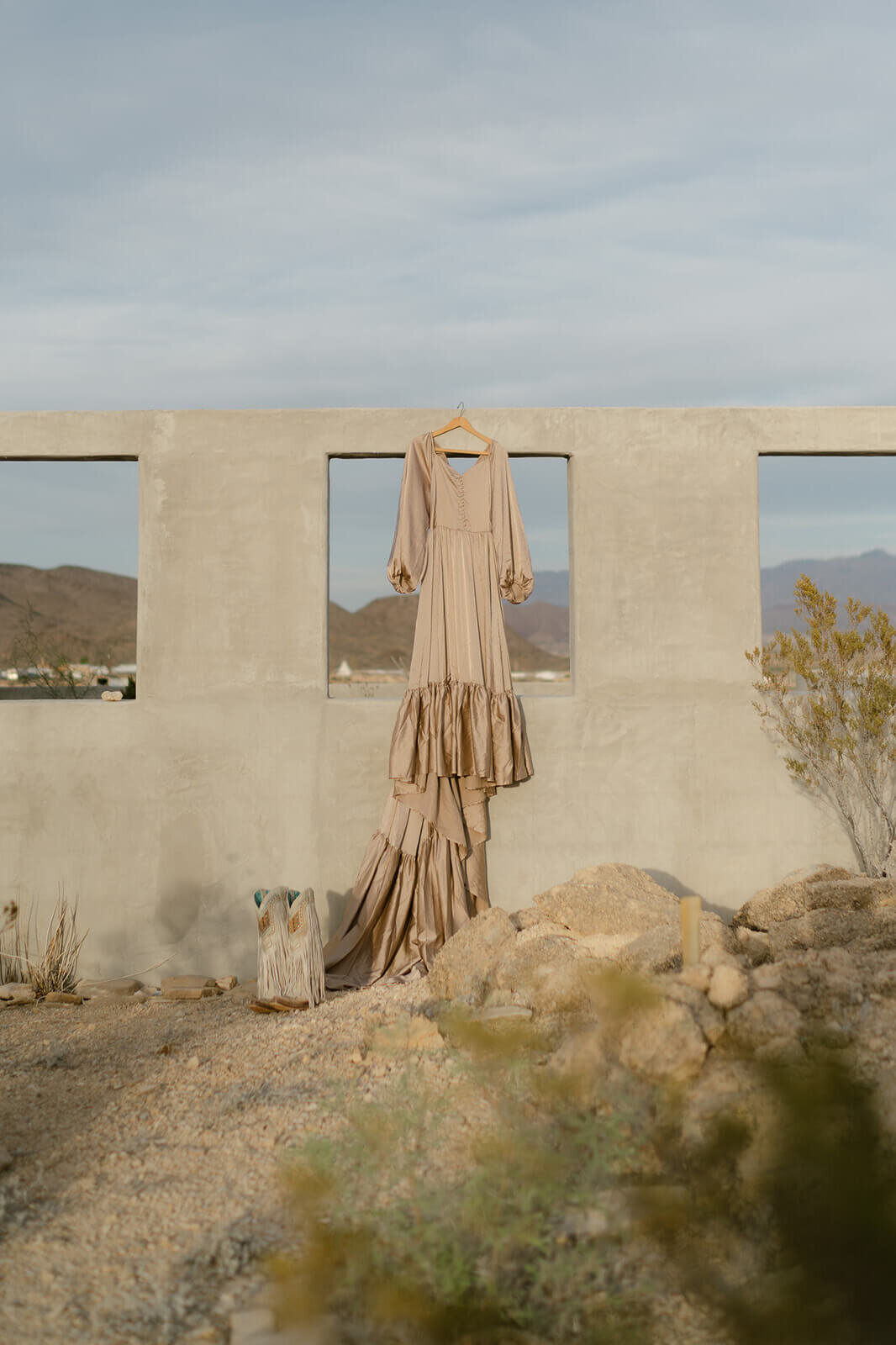 dress hanging on stucco wall with mountains behind