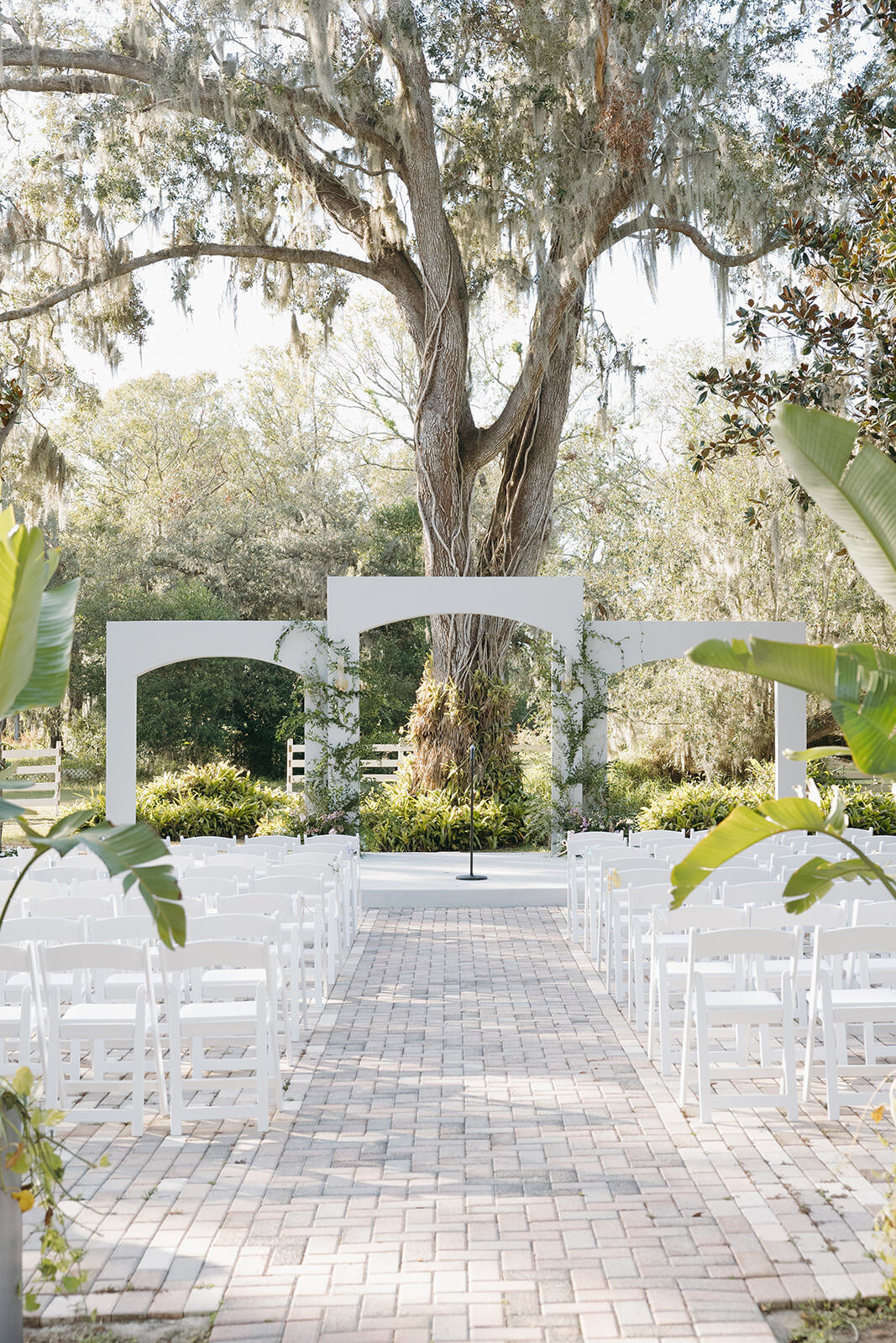 White ceremony chairs facing a lush floral arch at Uliana Estate in Lakeland Florida.